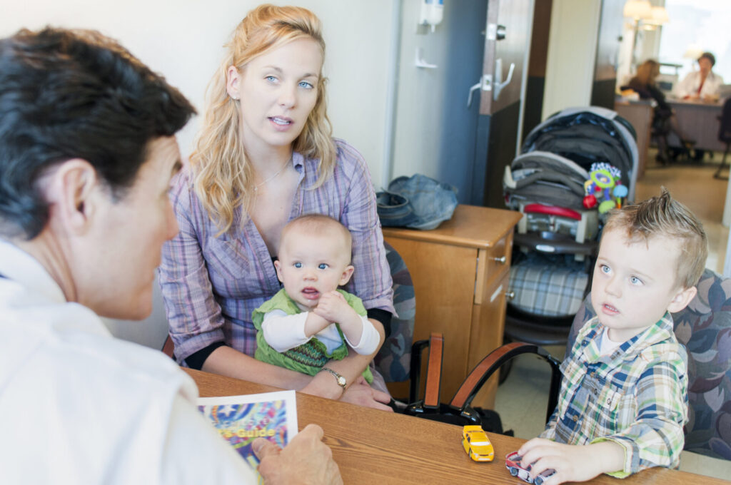 Mother sitting with two children, having an appointment with male