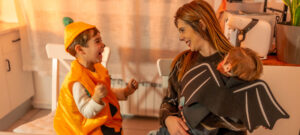 Mother and children celebrating halloween together, wearing colourful costumes, smiling joyfully in a cosy kitchen filled with festive decorations